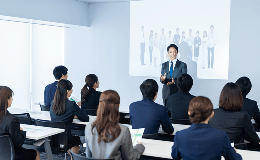 会議室で複数人の前で説明している男性の写真