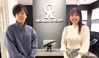 マネックス証券株式会社のロゴの前に立つ担当者二人の写真