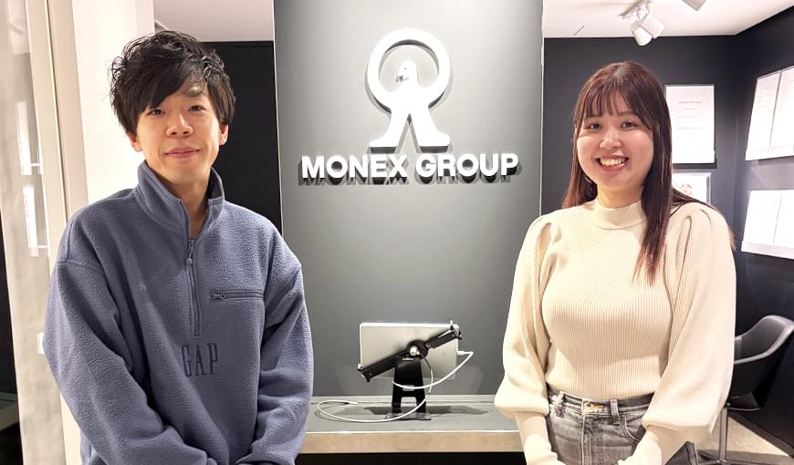 マネックス証券株式会社のロゴの前に座る担当者の写真