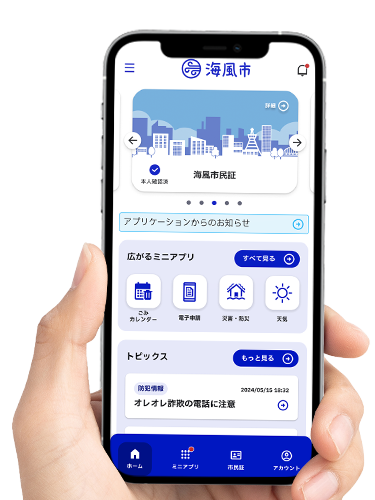 スマホに自治体向けアプリのホーム画面が表示されているスマホを持つ手。