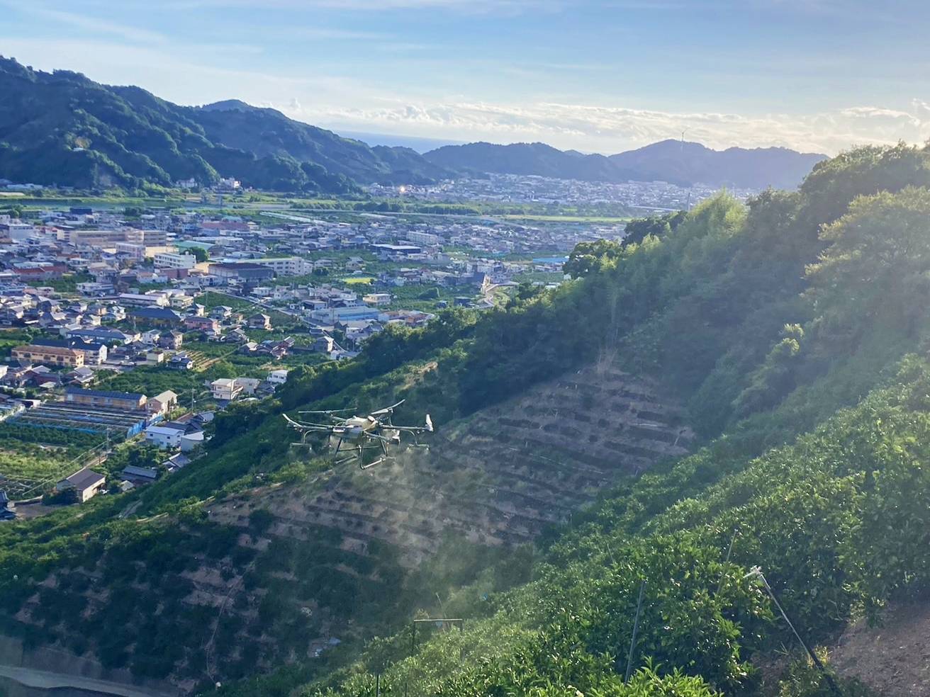 山間部の斜面で農薬散布を行う農業用ドローン